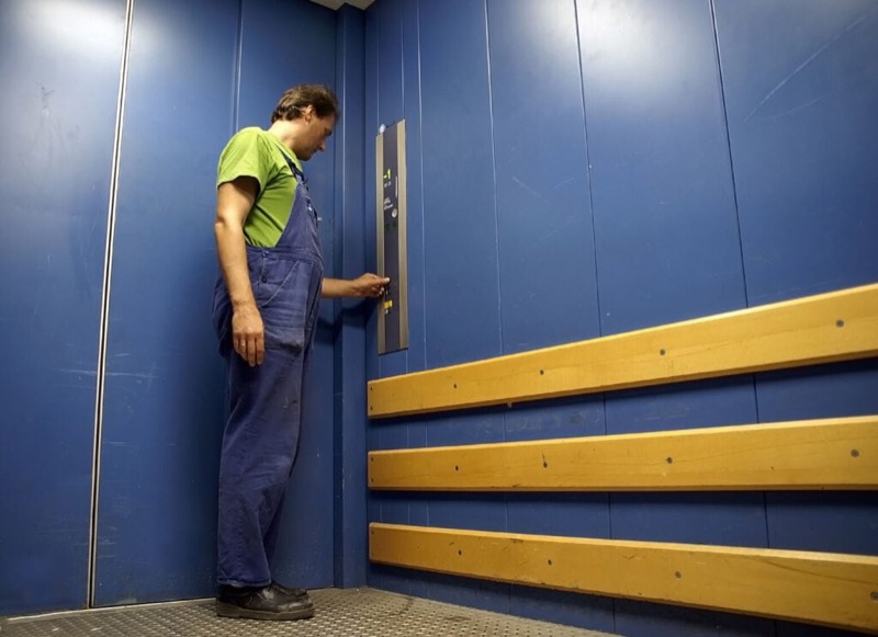 Bên trong cabin thang máy tải hàng — tường sơn tĩnh điện, thanh chắn va đập gỗ, sàn chống trượt